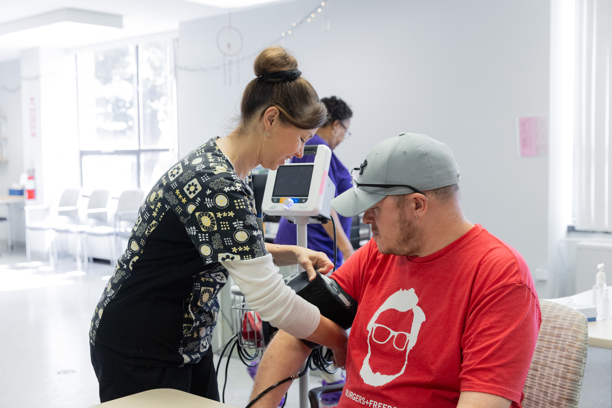Nurse taking blood pressure of patient in red shirt